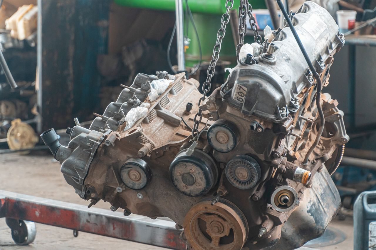 Bloc moteur déposé, suspendu par des chaînes à une grue d'atelier